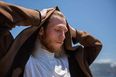 Portrait of young man looking away against sky