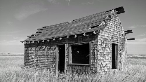 Abandoned house on field against sky