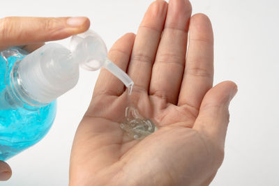 Close-up of hand holding bottle against white background