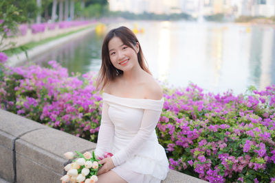 Portrait of young woman standing against plants