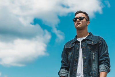 Low angle view of man wearing sunglasses standing against sky