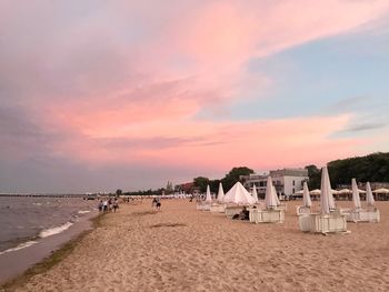 People on beach against sky during sunset