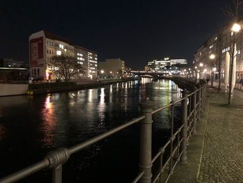 Illuminated bridge over river in city at night
