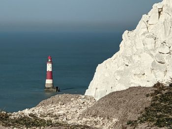 Lighthouse by sea against sky