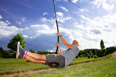 Man holding umbrella on field against sky