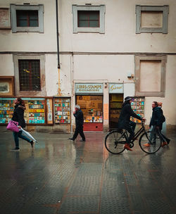 People riding bicycle on street against buildings in city