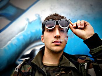 Portrait of young man smoking while wearing sunglasses