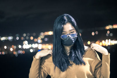 Portrait of young woman wearing eyeglasses at night