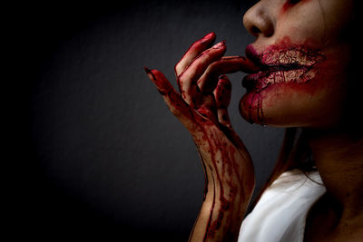 Side view of young woman with halloween make-up against wall