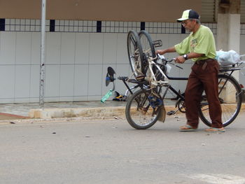 Man with bicycle standing on street