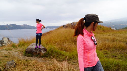 Rear view of women standing on field against sky