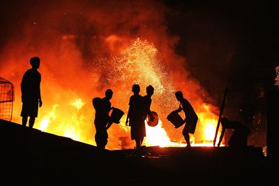 Silhouette people extinguishing fire at night