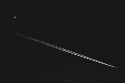 Low angle view of airplane flying against sky at night