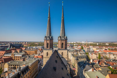 Aerial view of buildings in city against clear blue sky