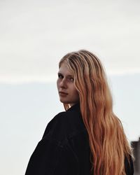 Close-up of young woman standing against sky