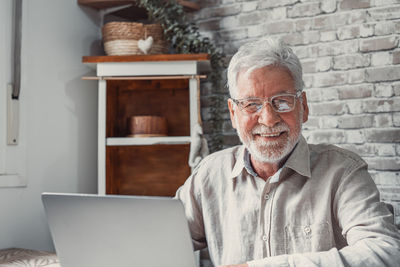 Portrait of senior man using laptop while sitting in office