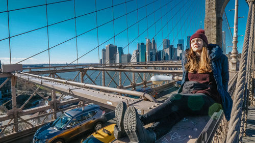 Portrait of young woman on bridge against sky