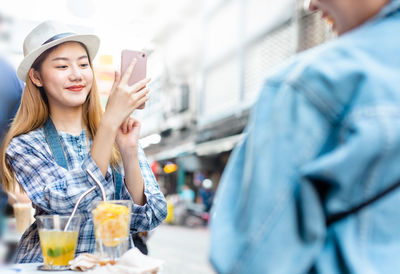 Portrait of smiling woman holding mobile phone outdoors