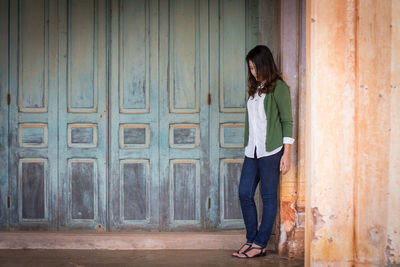 Full length of woman standing against door