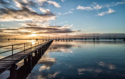 Pier over sea against sky during sunset