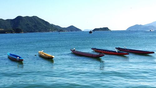 Boats moored in sea against clear sky