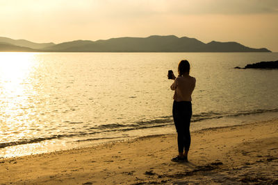 Rear view of woman standing on shore at beach