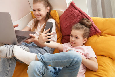 Sisters using laptop while lying in bed