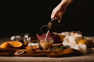 Pouring milk in black tea set-up against black background 