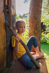 Girl plays in creative handmade treehouse in backyard, summer activity, happy childhood, cottagecore