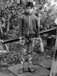 Portrait of boy standing by tree