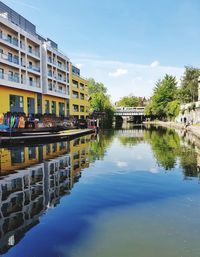 Canal by buildings against sky in city