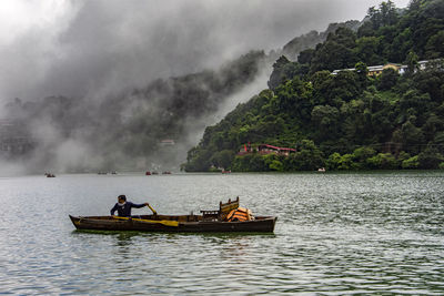 People in boat on lake against sky
