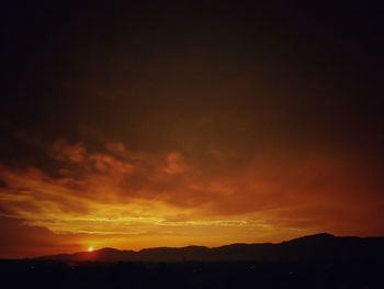Scenic view of dramatic sky over silhouette landscape