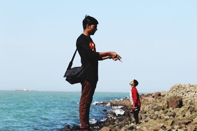 Full length of man standing on beach against clear sky