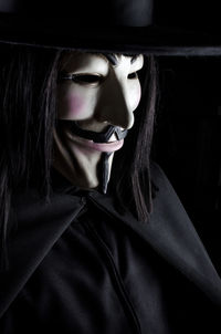 Close-up of person wearing mask against black background