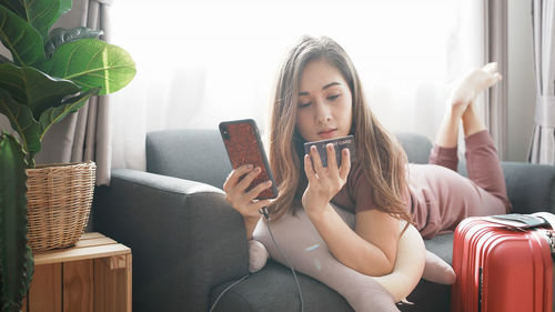 Smiling woman online shopping though mobile phone at home