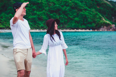 Rear view of friends standing at sea shore