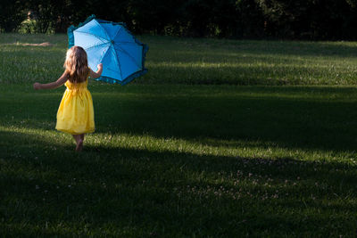 Woman with umbrella standing on field