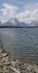 Scenic view of lake by snowcapped mountains against sky