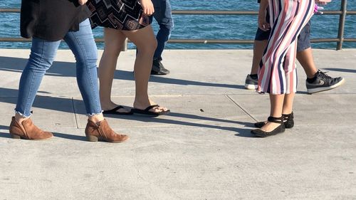 Low section of people walking on footpath by lake