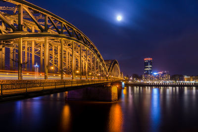 Illuminated bridge over river at night