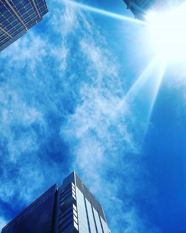 architecture, low angle view, building exterior, built structure, sky, cloud - sky, modern, sunbeam, sunlight, sun, city, blue, skyscraper, office building, cloud, directly below, glass - material, day, building, tall - high