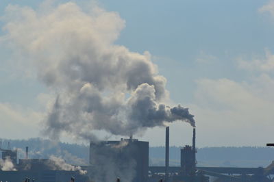 Smoke emitting from chimney against sky