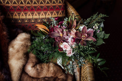 High angle view of bouquet and fur on wicker chair at home