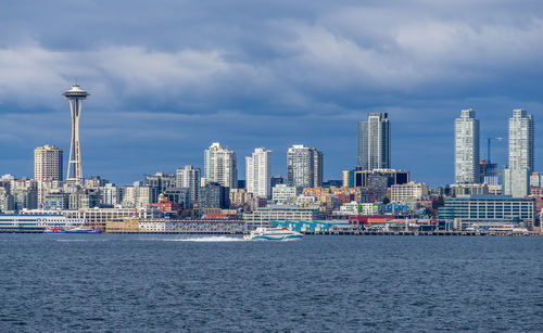 A water taxi cruises across elliott bay in front of the seattle skyline.