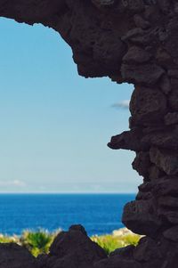 Rock formations by sea against clear blue sky