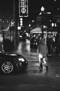 Rear view of man on illuminated street at night