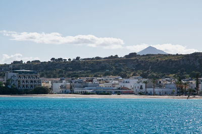 Scenic view of sea by buildings against sky