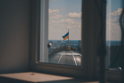 Low angle view of flags against sky seen through window