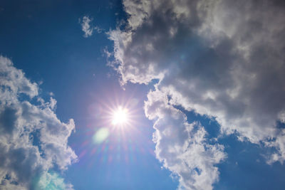 Low angle view of sunlight streaming through clouds